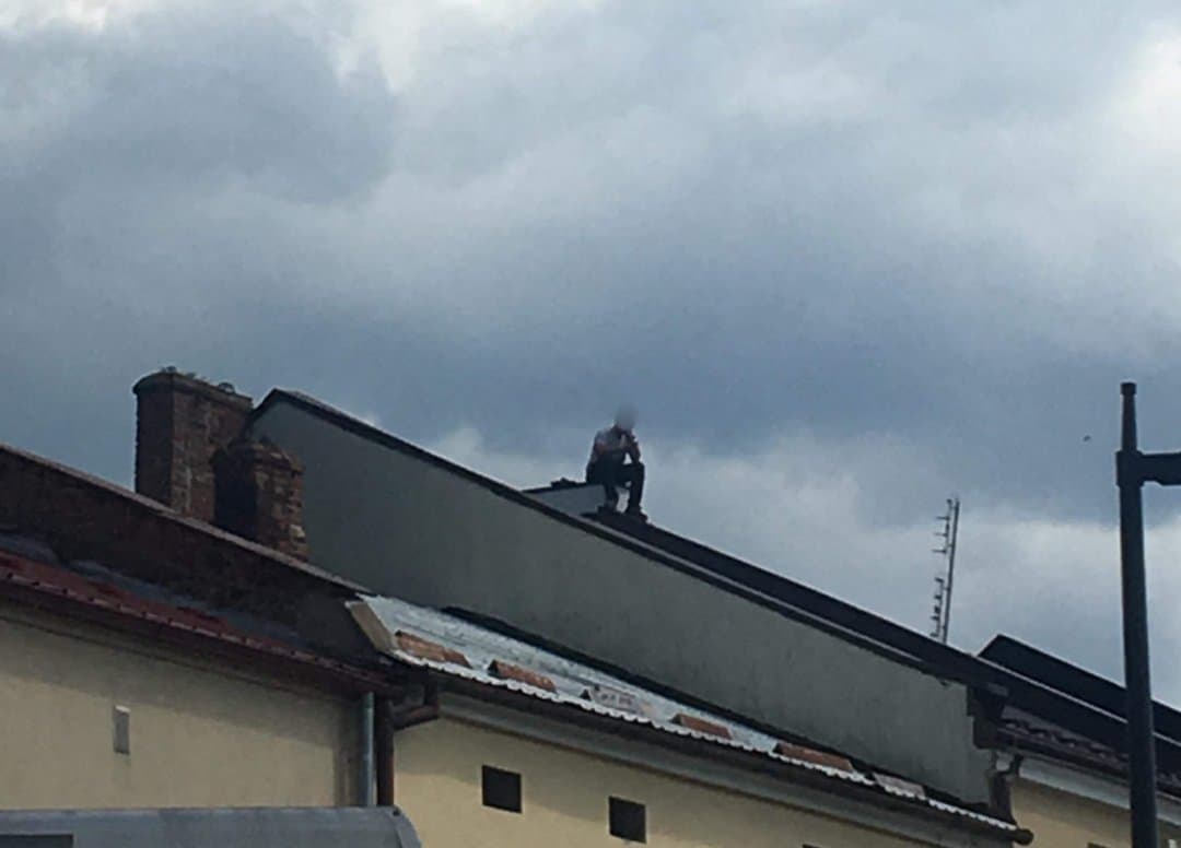 Mężczyzna siedzi na dachu kamienicy w Mielcu - Zdjęcie główne